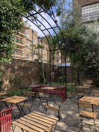 Empty chairs and tables in park against building