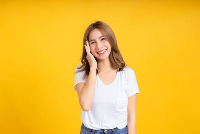 Portrait of a smiling young woman against yellow background