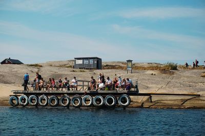 People on shore against sky