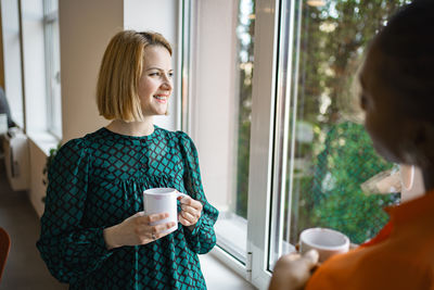 Side view of young woman looking through window