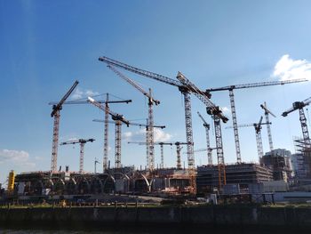 Construction cranes against sky