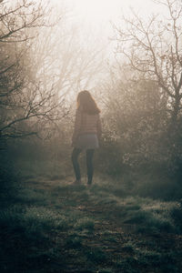 Rear view of woman walking on field