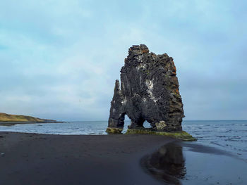 Rock formation on beach against sky