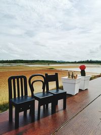 Rear view of chairs and tables at beach against sky