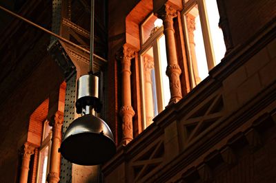 Low angle view of electric lamp hanging outside building