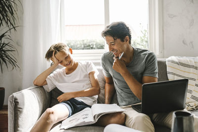 Friends sitting on window at home