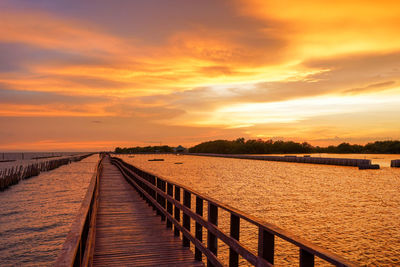 Pier over sea against sky during sunset