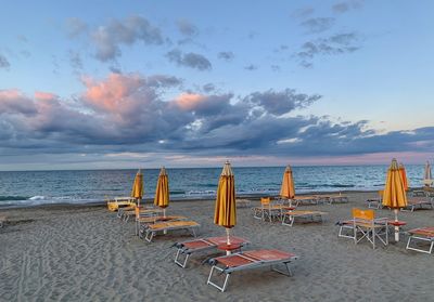 Empty chairs on beach against sky