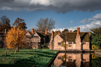 Houses by lake and buildings against sky