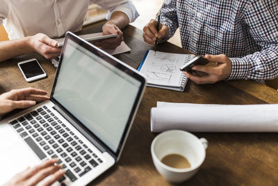 Colleagues at desk with smartphone, laptop and notepad