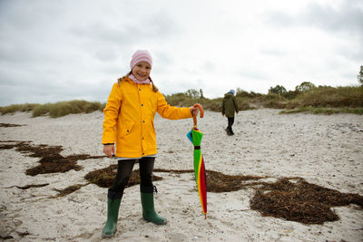 Full length portrait of girl holding umbrella at beach