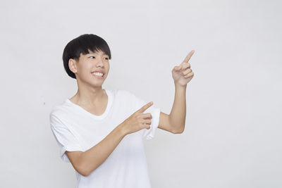 Portrait of smiling young woman standing against white background
