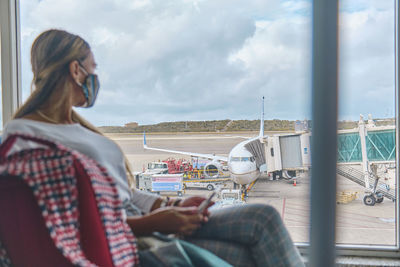 Side view of young woman looking through window