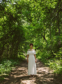 Portrait of woman standing by tree in forest