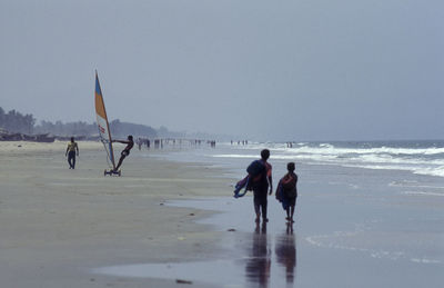 Rear view of woman walking at beach against clear sky