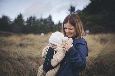 A woman with an infant is standing on the californian beach