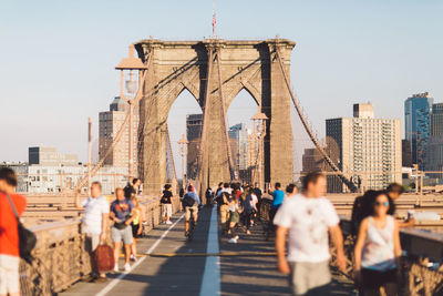 People on suspension bridge in city