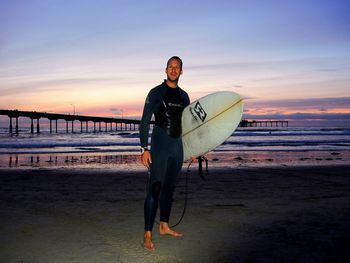 Portrait of young man with surfboard on beach