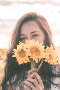 Portrait of beautiful young woman holding red flowering plant