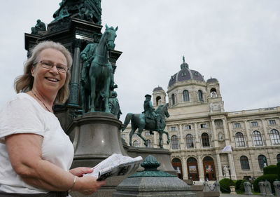 Smiling woman holding map while standing against hofburg palace