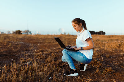 Side view of woman sitting on field