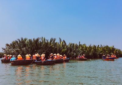 People on boat sailing in river against clear sky