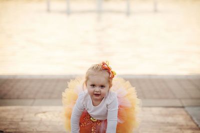 Portrait of cute girl in tutu crouching on footpath