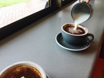 Cropped hand making coffee on table