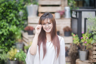 Smiling young woman against blurred plants