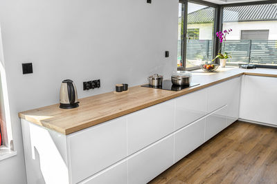 Metal pots on an induction cooker built into the kitchen worktop, on the cabinets, electric kettle. 