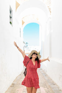 Woman wearing hat standing against building