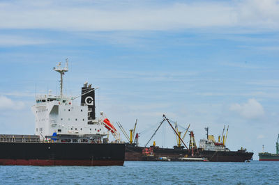 Cranes at commercial dock against sky