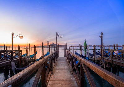 Pier on sea against clear sky at sunset