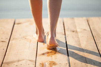 Low section of wet woman on wooden jetty