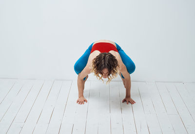 Full length of young woman jumping against white background