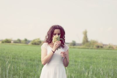 Full length of woman holding umbrella while standing on field against sky