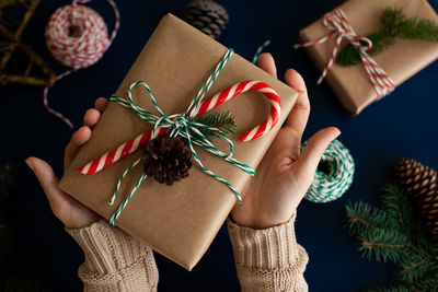 Woman wraps a handmade eco style christmas present in kraft paper and natural spruce branches 
