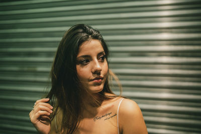 Beautiful young woman looking away against closed shutter