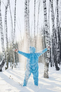 Woman with arms outstretched in forest during winter