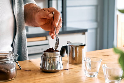 Man preparing classic italian coffee in the mocha, filling funnel of a moka pot with ground coffee. 