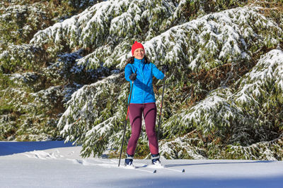 Full length of woman standing on snow covered trees