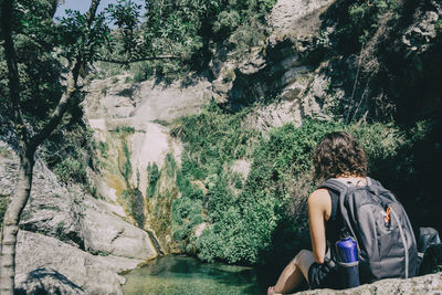 Rear view of man looking at waterfall in forest