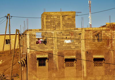 Rear view of man working on building against clear sky