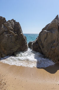 Rocks on beach against clear sky