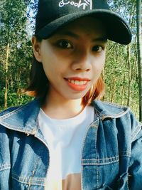 Portrait of smiling young woman standing in forest