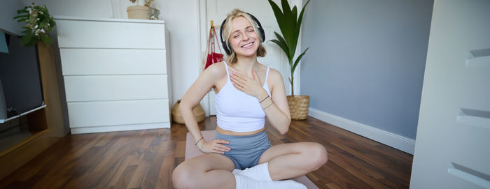 Portrait of young woman sitting on floor at home