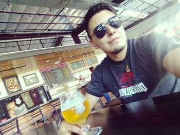 Portrait of young man with drink on table