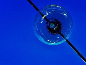 Close-up of electric lamp against clear blue sky