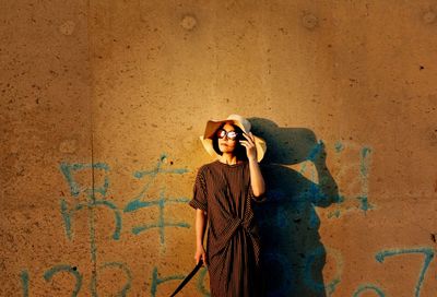 Full length portrait of young man standing against wall