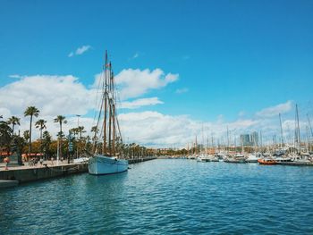 Boats moored at port de barcelona against sky